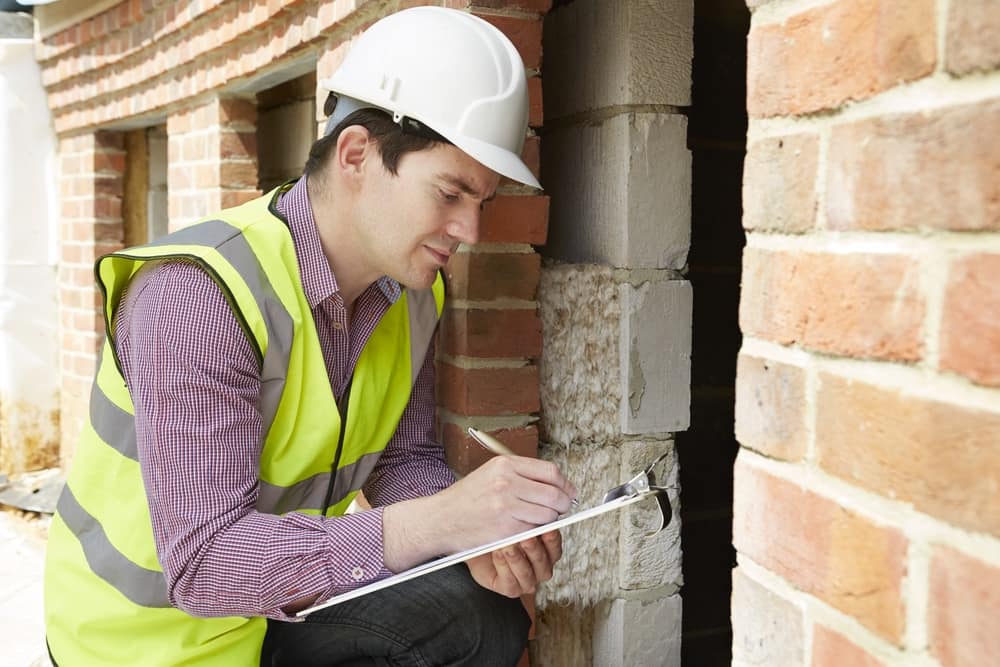Man checking a home holding a clip board